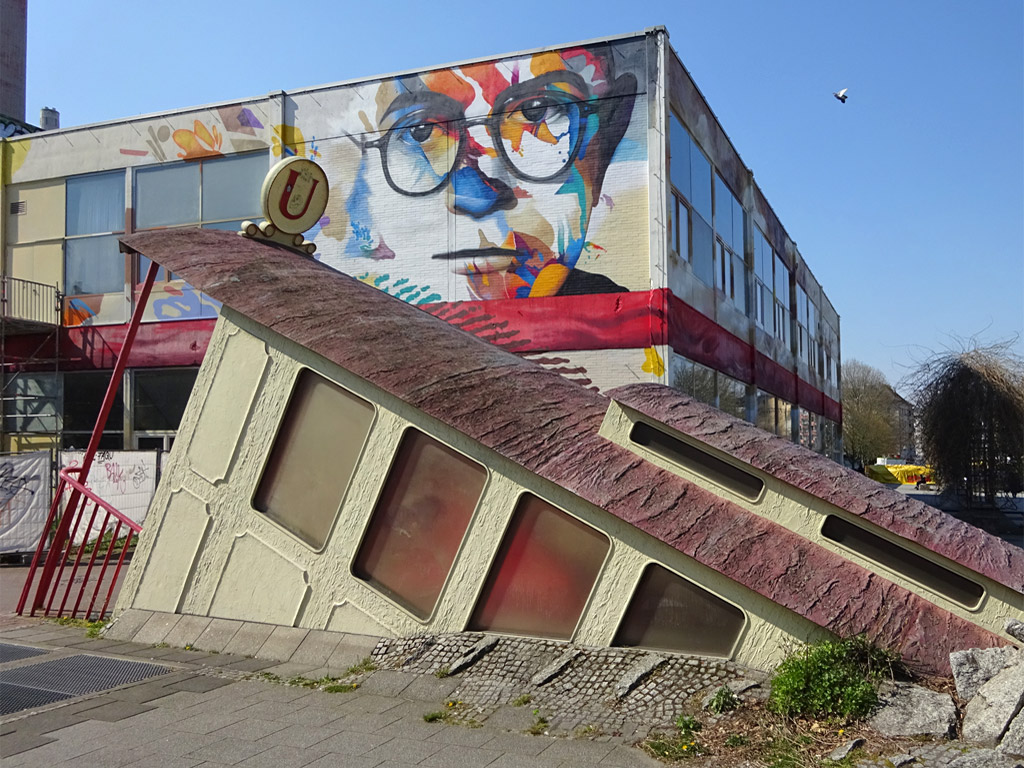 Gebäude-Mural mit roter Geschenkschleife und Antlitze von Adorno und Horkheimer