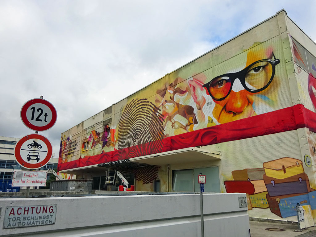 Gebäude-Mural mit roter Geschenkschleife und Antlitze von Adorno und Horkheimer
