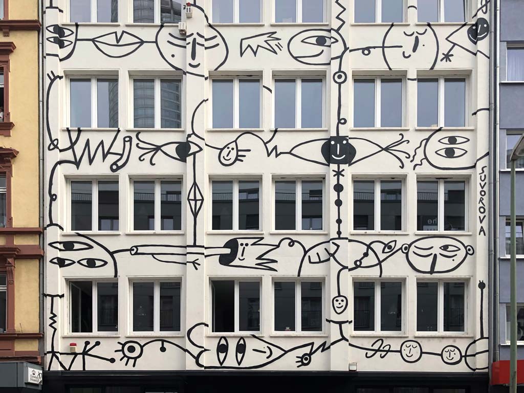 Schwarz-weiß-Illustration mit mehräugigen Gesichtern an Fassade im Bahnhofsviertel