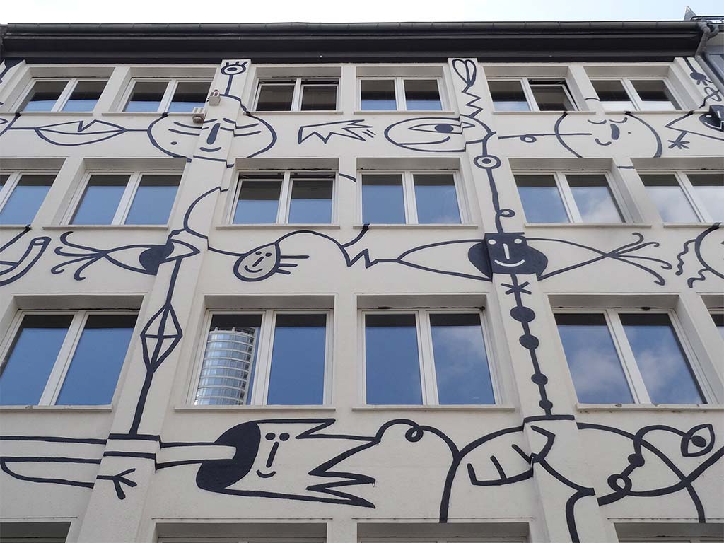 Schwarz-weiß-Illustration mit mehräugigen Gesichtern an Fassade im Bahnhofsviertel