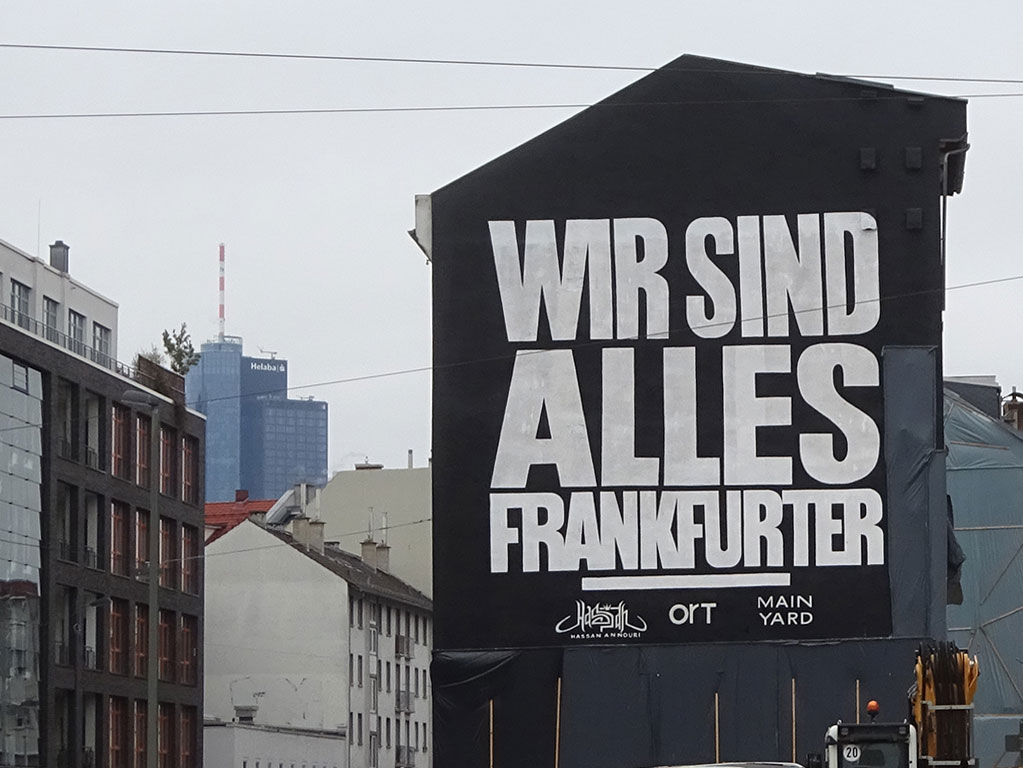 Wir sind alles Frankfurter - Parole in weiß auf schwarz an Hausfassade im Frankfurter Allerheiligenviertel